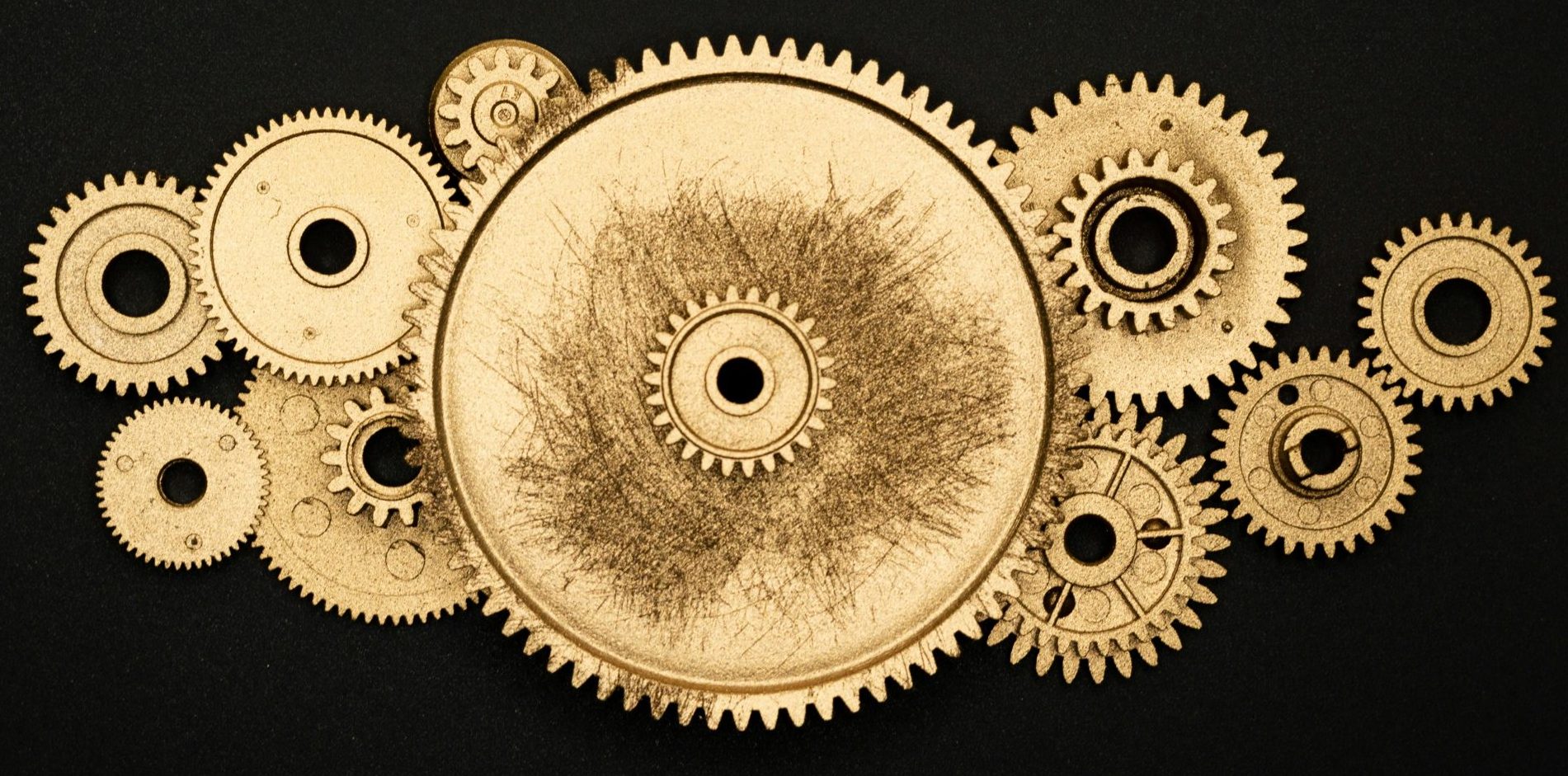Artistic arrangement of gold gears on a black background symbolizing industry.